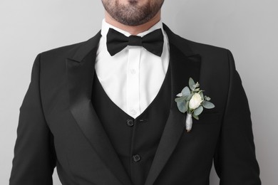 Photo of Groom with boutonniere on light grey background, closeup. Wedding accessory