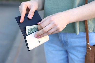 Woman holding purse with banknotes outdoors, closeup