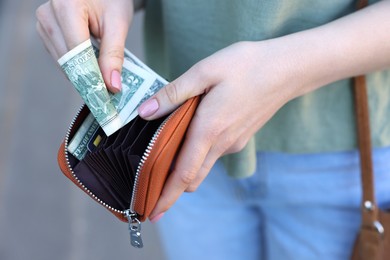 Photo of Woman holding purse with banknotes outdoors, closeup