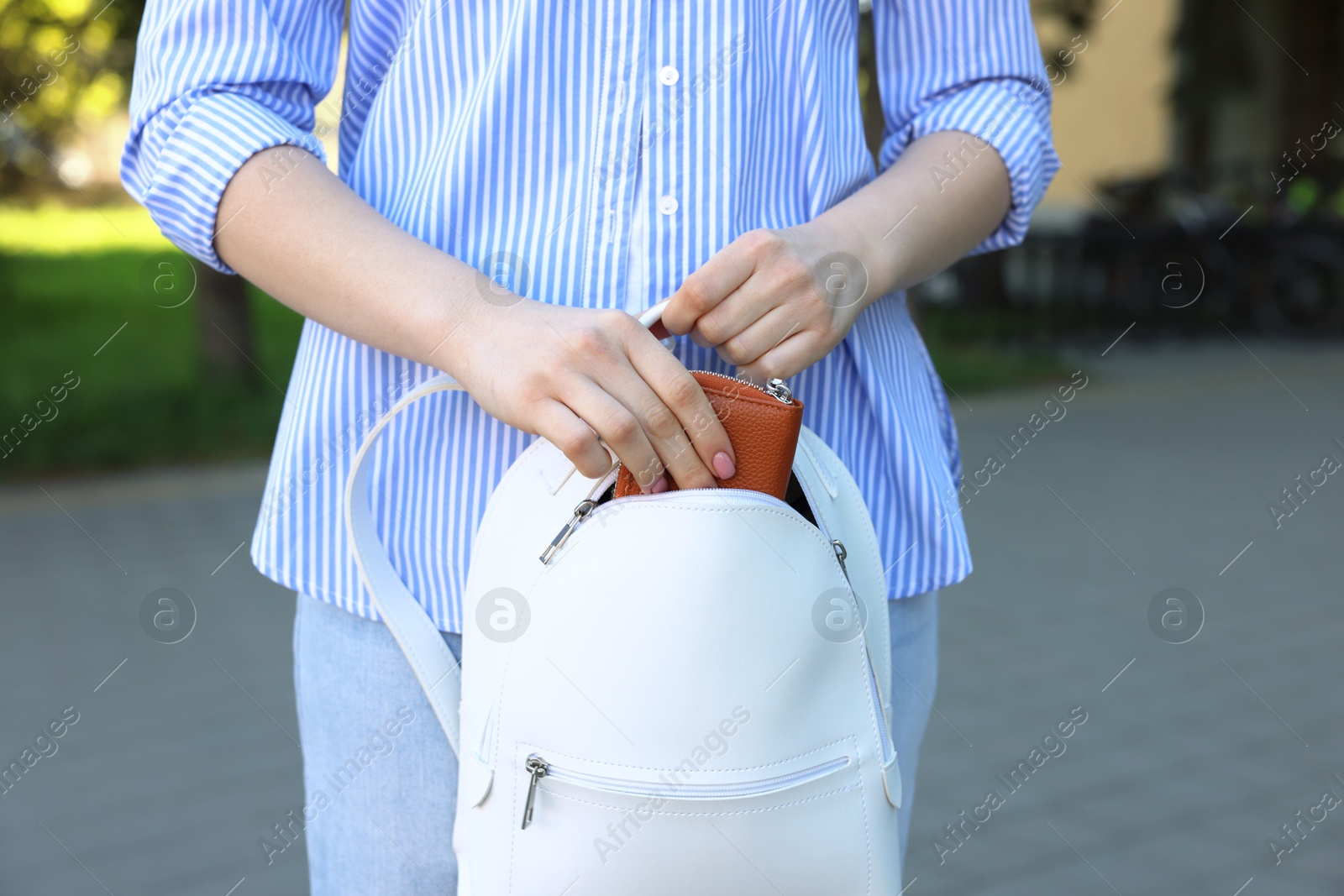 Photo of Woman putting purse into bag outdoors, closeup