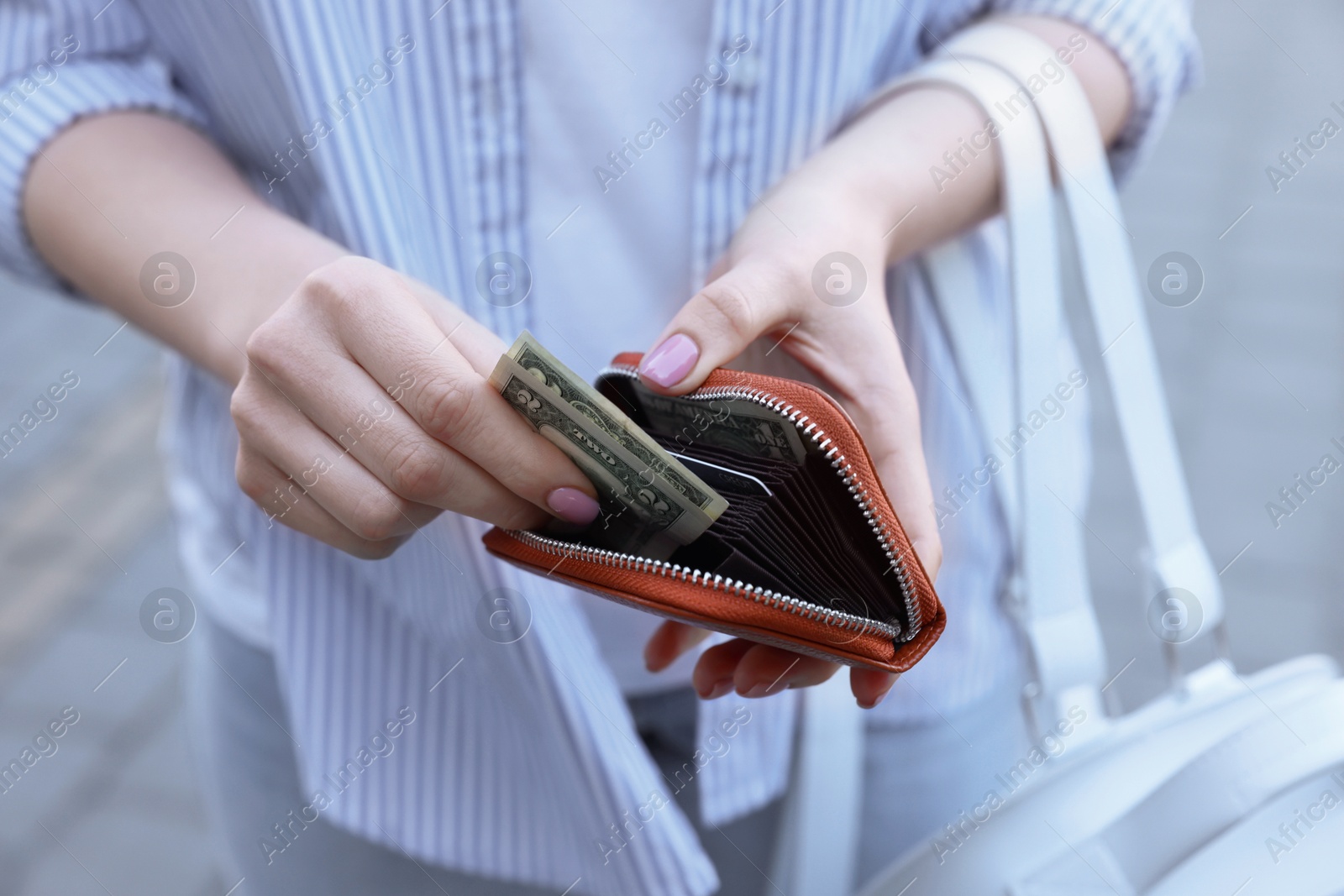 Photo of Woman holding purse with banknotes outdoors, closeup