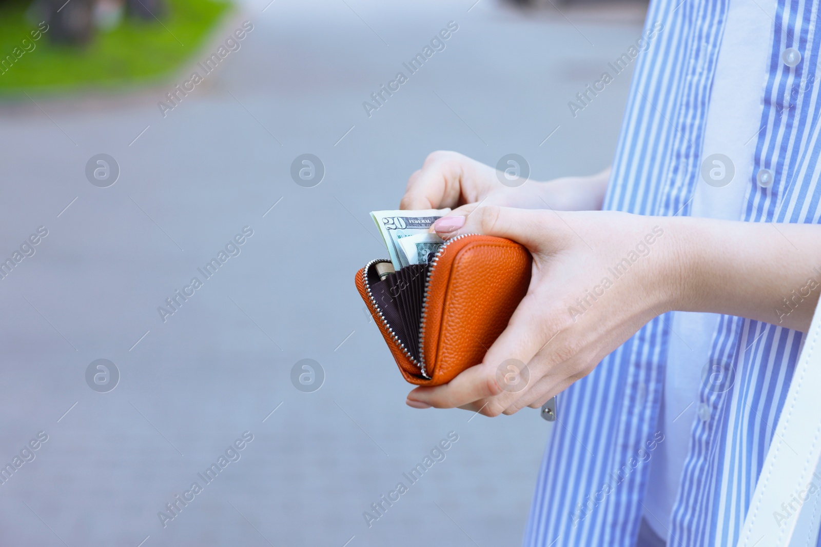 Photo of Woman holding purse with banknotes outdoors, closeup. Space for text