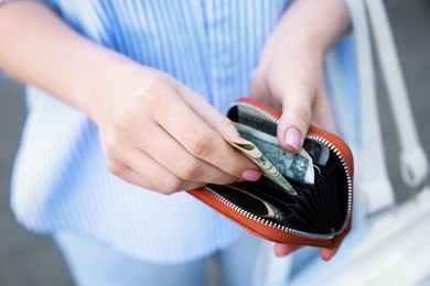 Photo of Woman holding purse with banknotes outdoors, closeup