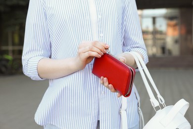 Photo of Woman holding stylish red purse outdoors, closeup