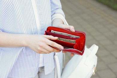 Woman holding purse with banknotes outdoors, closeup