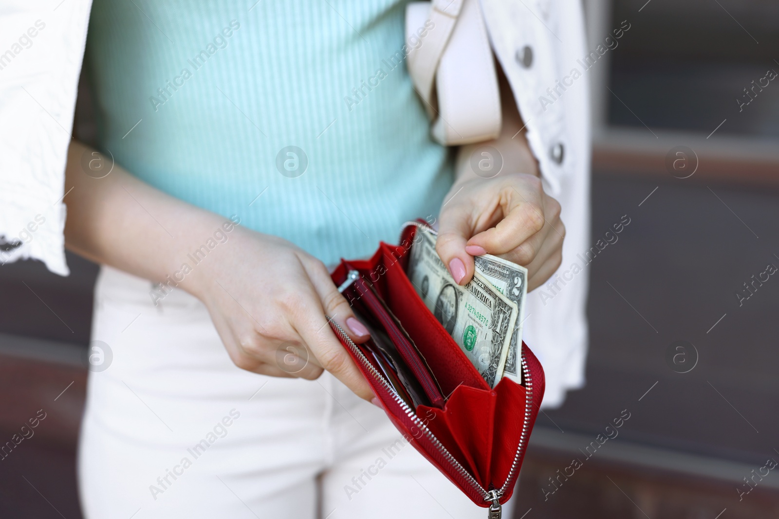 Photo of Woman holding purse with banknotes outdoors, closeup