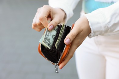 Woman holding purse with banknotes outdoors, closeup