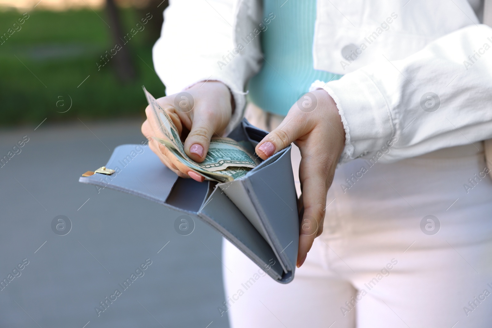 Photo of Woman holding purse with banknotes outdoors, closeup