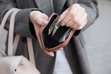 Photo of Woman holding purse with banknotes outdoors, closeup