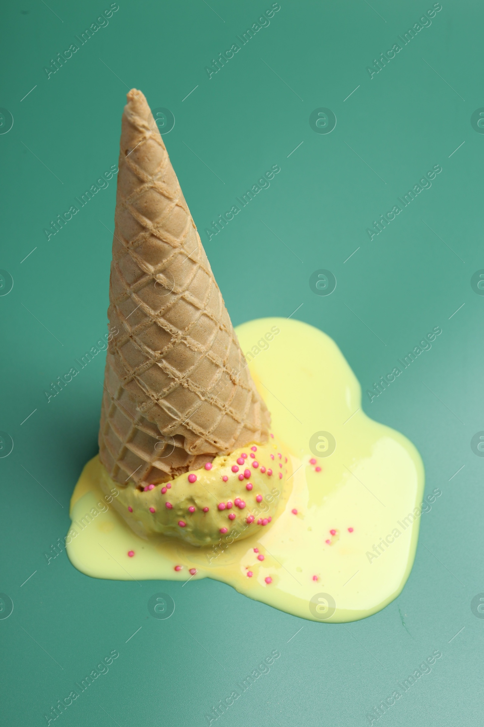 Photo of Melted ice cream in wafer cone on pale green background