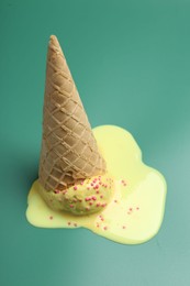 Melted ice cream in wafer cone on pale green background