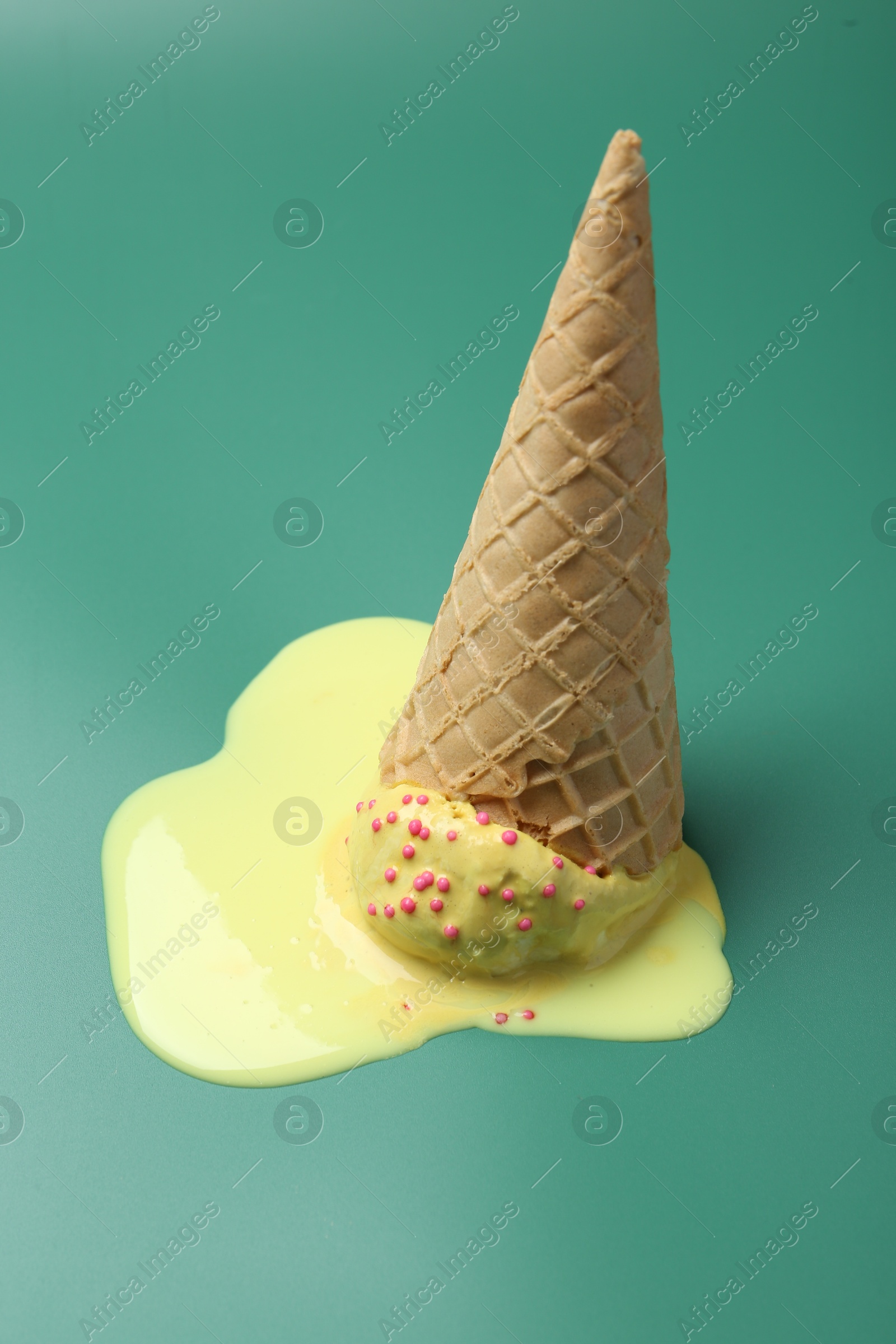 Photo of Melted ice cream in wafer cone on pale green background