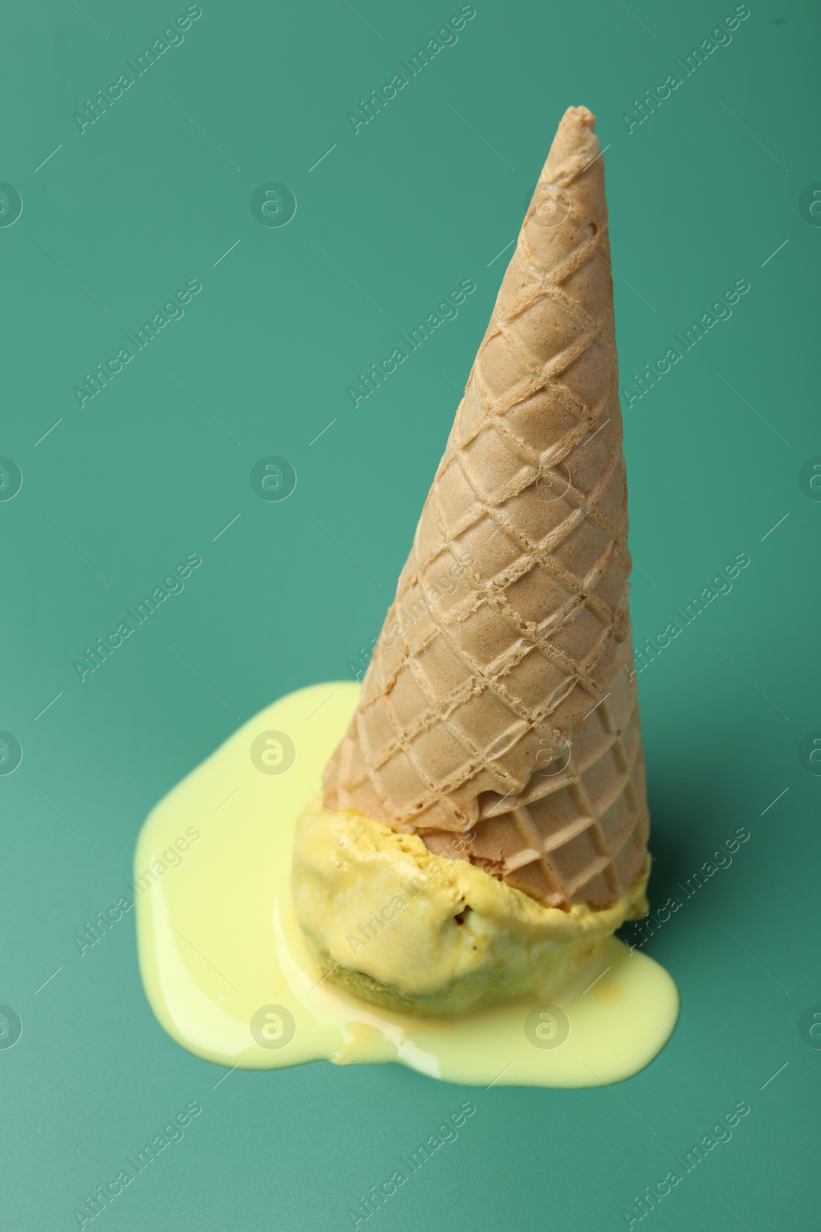 Photo of Melted ice cream in wafer cone on pale green background