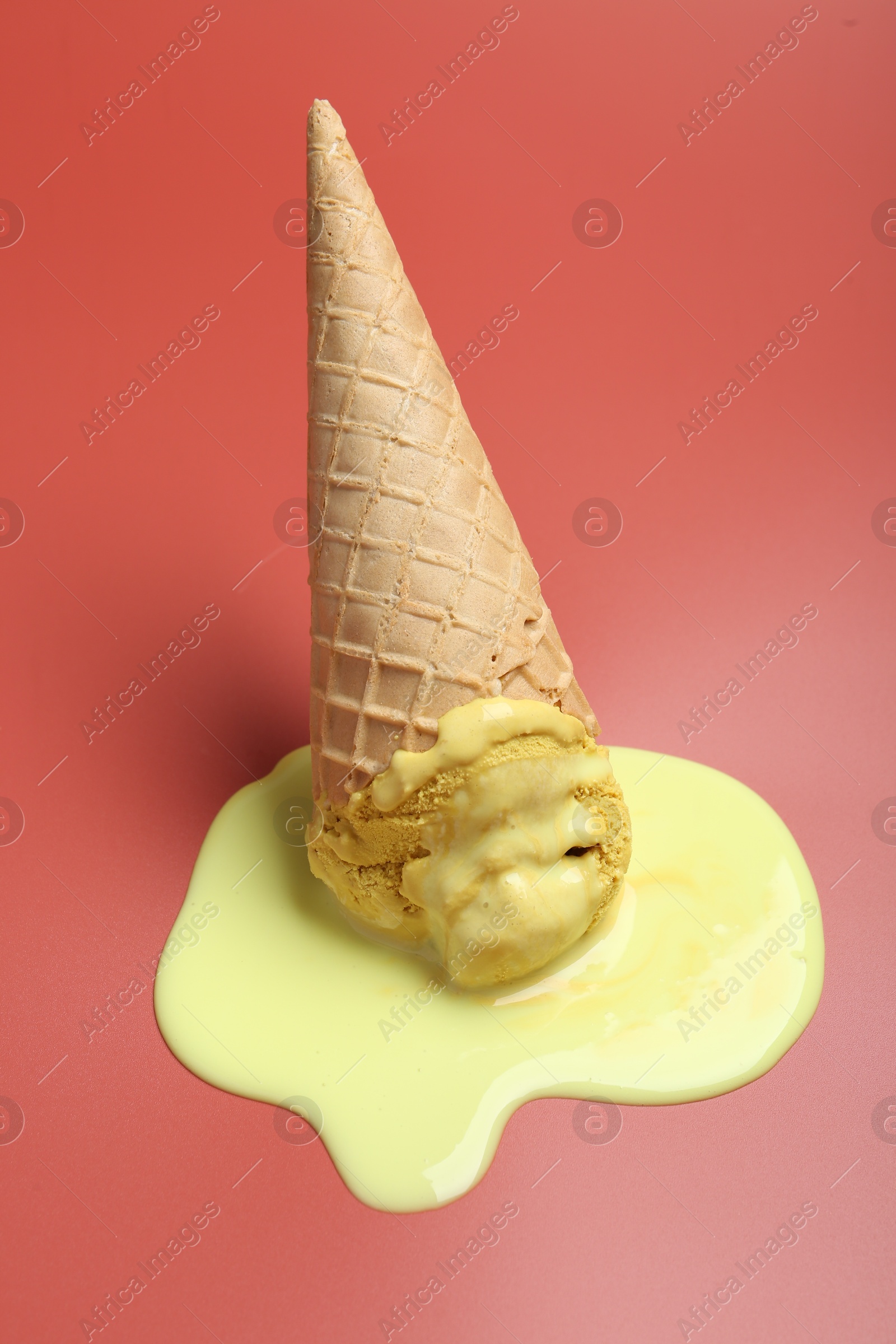 Photo of Melted ice cream in wafer cone on pale pink background