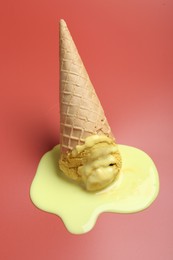 Melted ice cream in wafer cone on pale pink background