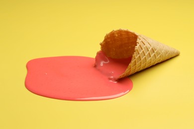 Melted ice cream and wafer cone on yellow background