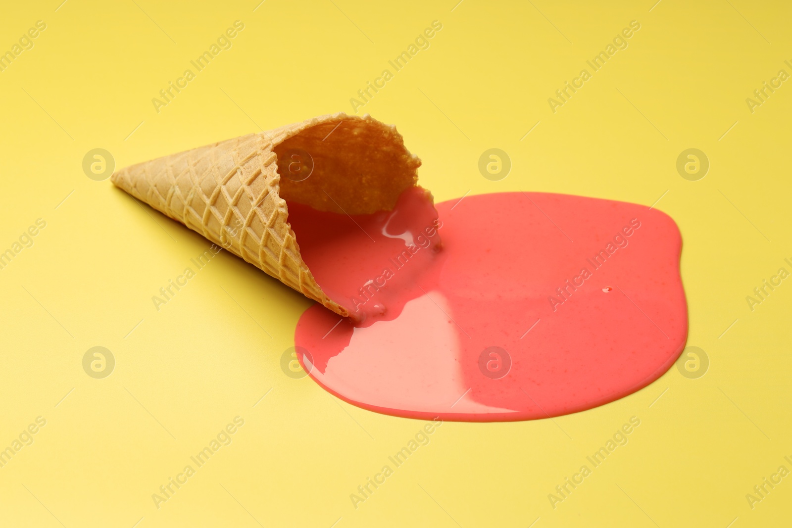 Photo of Melted ice cream and wafer cone on yellow background