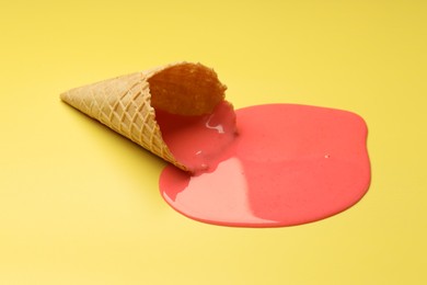 Melted ice cream and wafer cone on yellow background