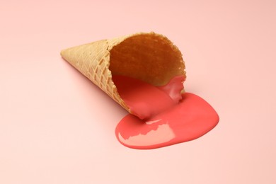 Photo of Melted ice cream and wafer cone on light pink background