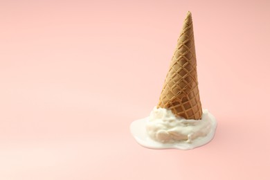 Photo of Melted ice cream in wafer cone on light pink background. Space for text