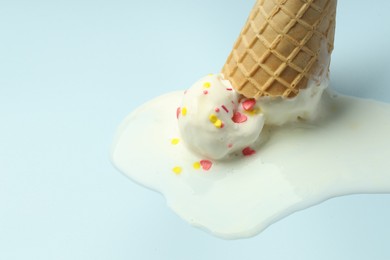 Photo of Melted ice cream in wafer cone on light background, closeup. Space for text
