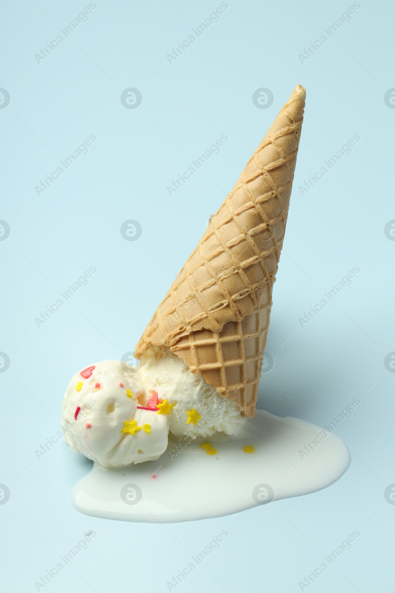 Photo of Melted ice cream in wafer cone on light background