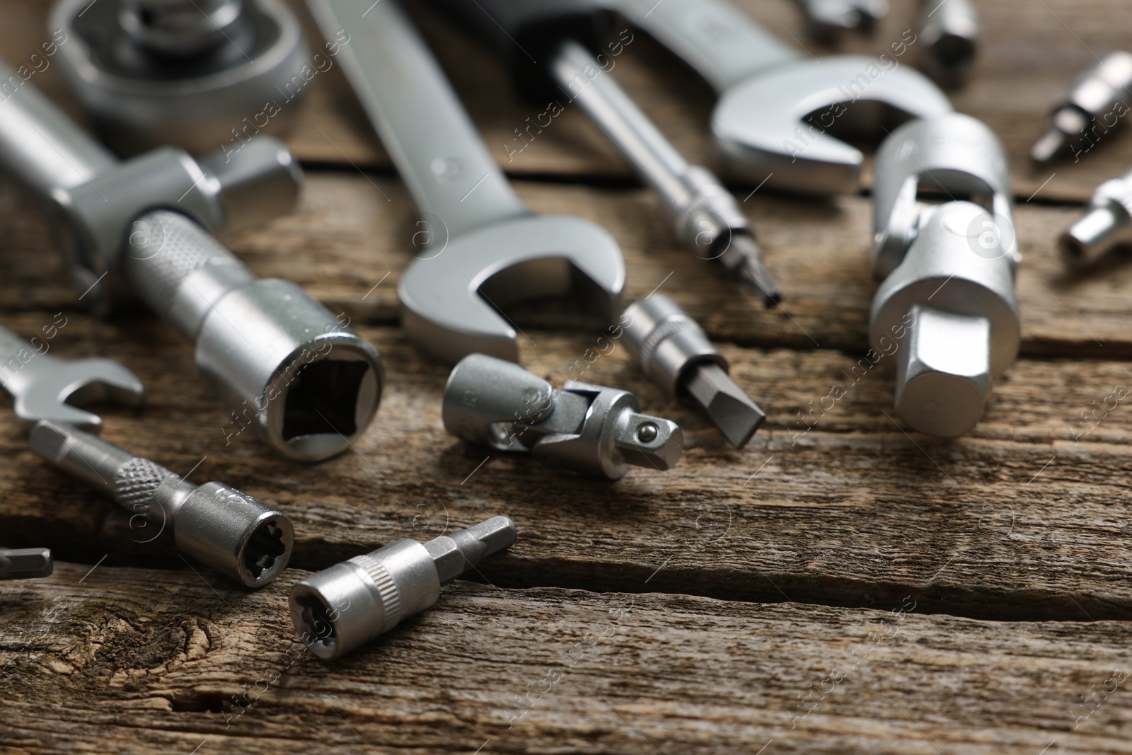 Photo of Different auto mechanic's tools on wooden table, closeup