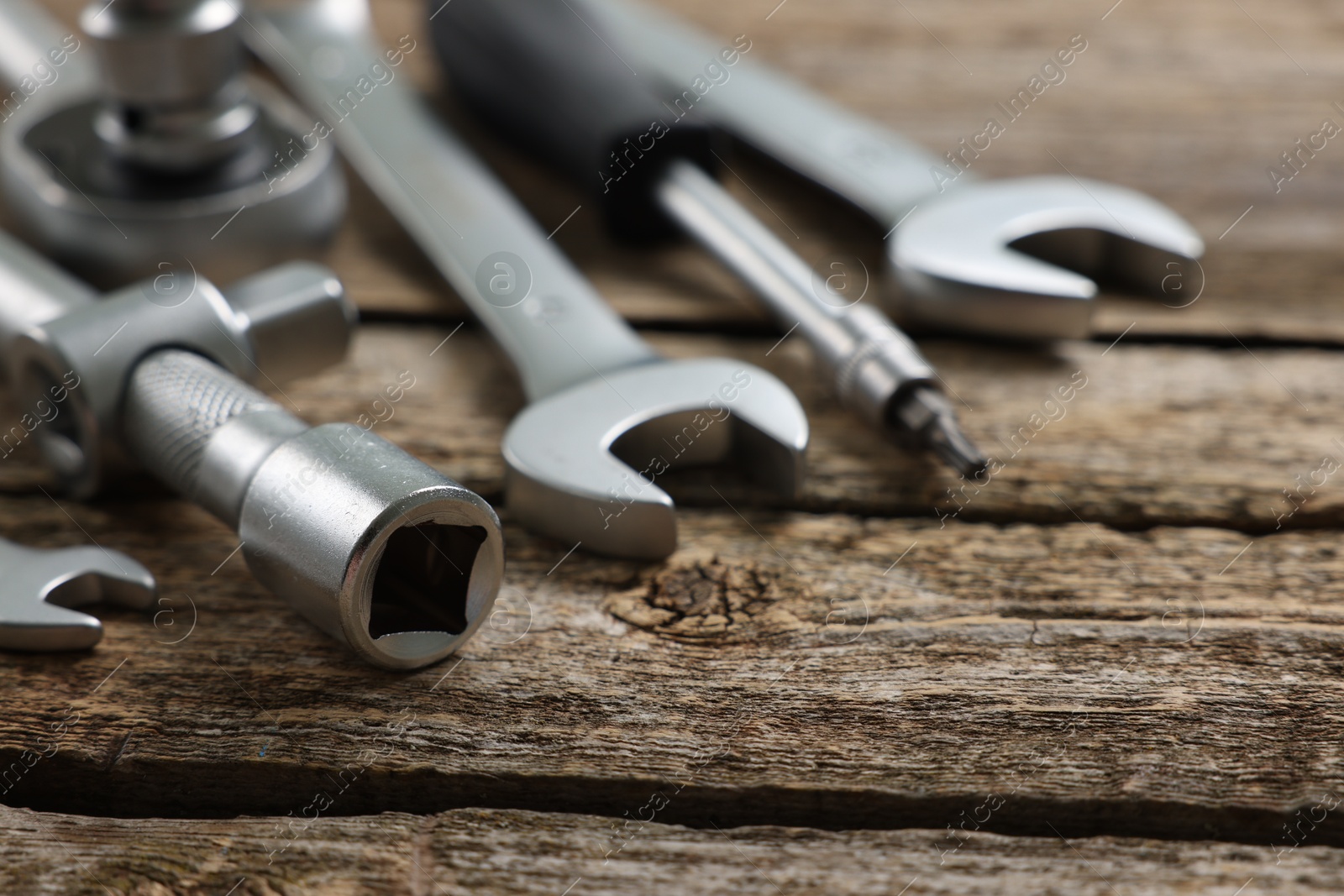 Photo of Different auto mechanic's tools on wooden table, closeup