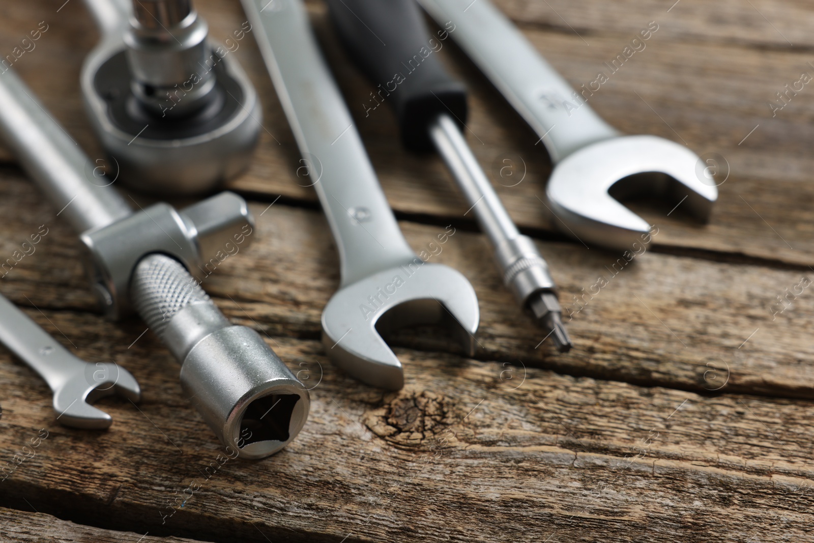 Photo of Different auto mechanic's tools on wooden table, closeup