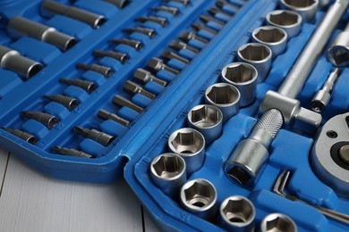 Auto mechanic's tools in plastic box on white wooden table, closeup