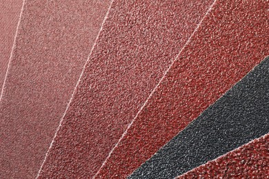 Photo of Many sheets of sandpaper as background, top view