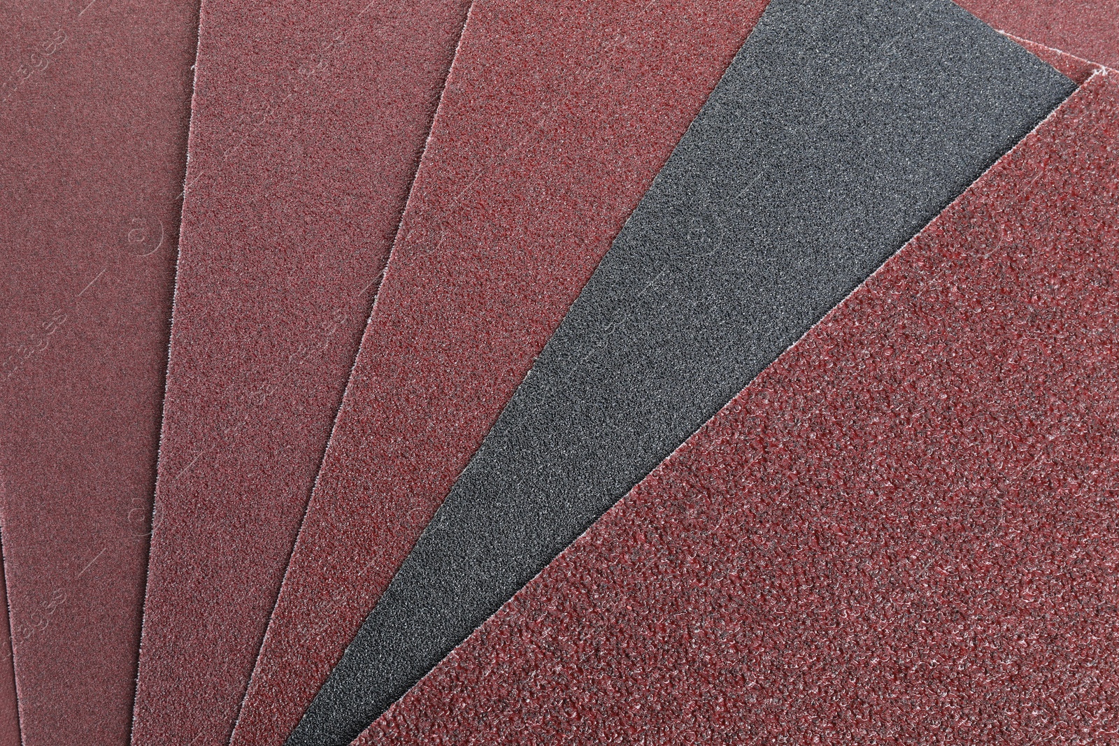 Photo of Many sheets of sandpaper as background, top view