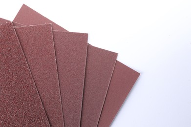 Photo of Sheets of sandpaper isolated on white, top view