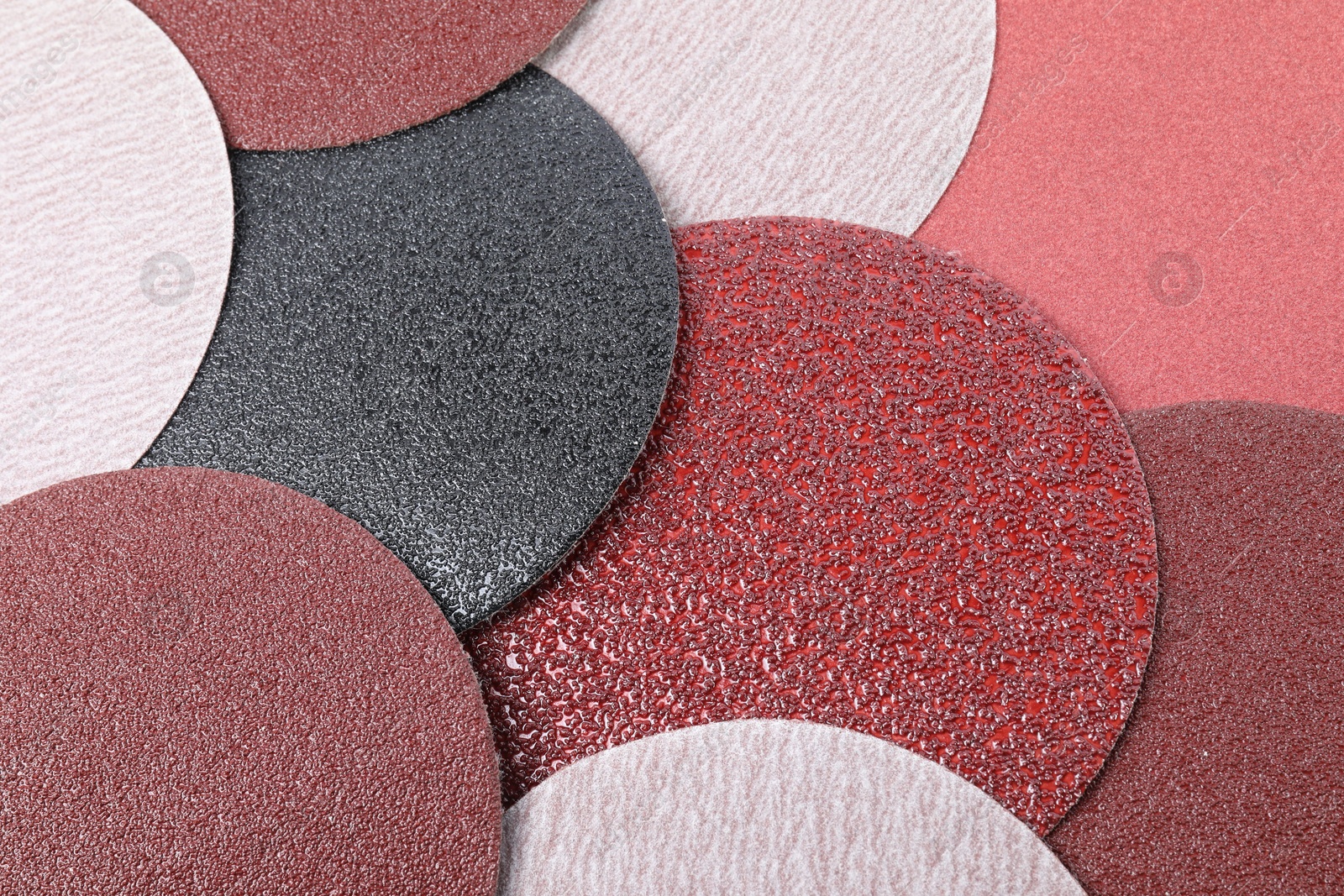 Photo of Many coarse sandpaper disks as background, closeup