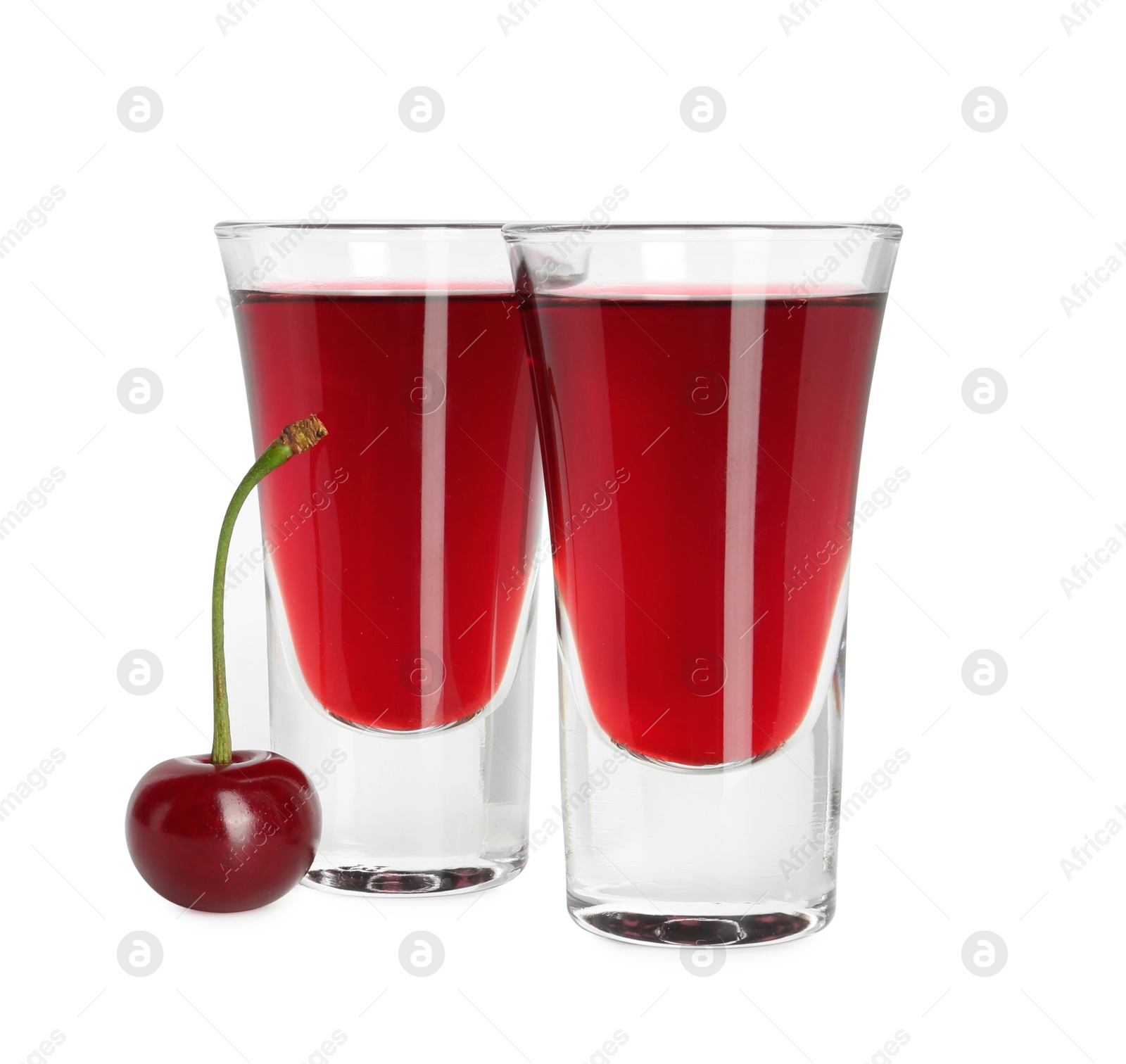 Photo of Shot glasses of delicious cherry liqueur and juicy berry isolated on white