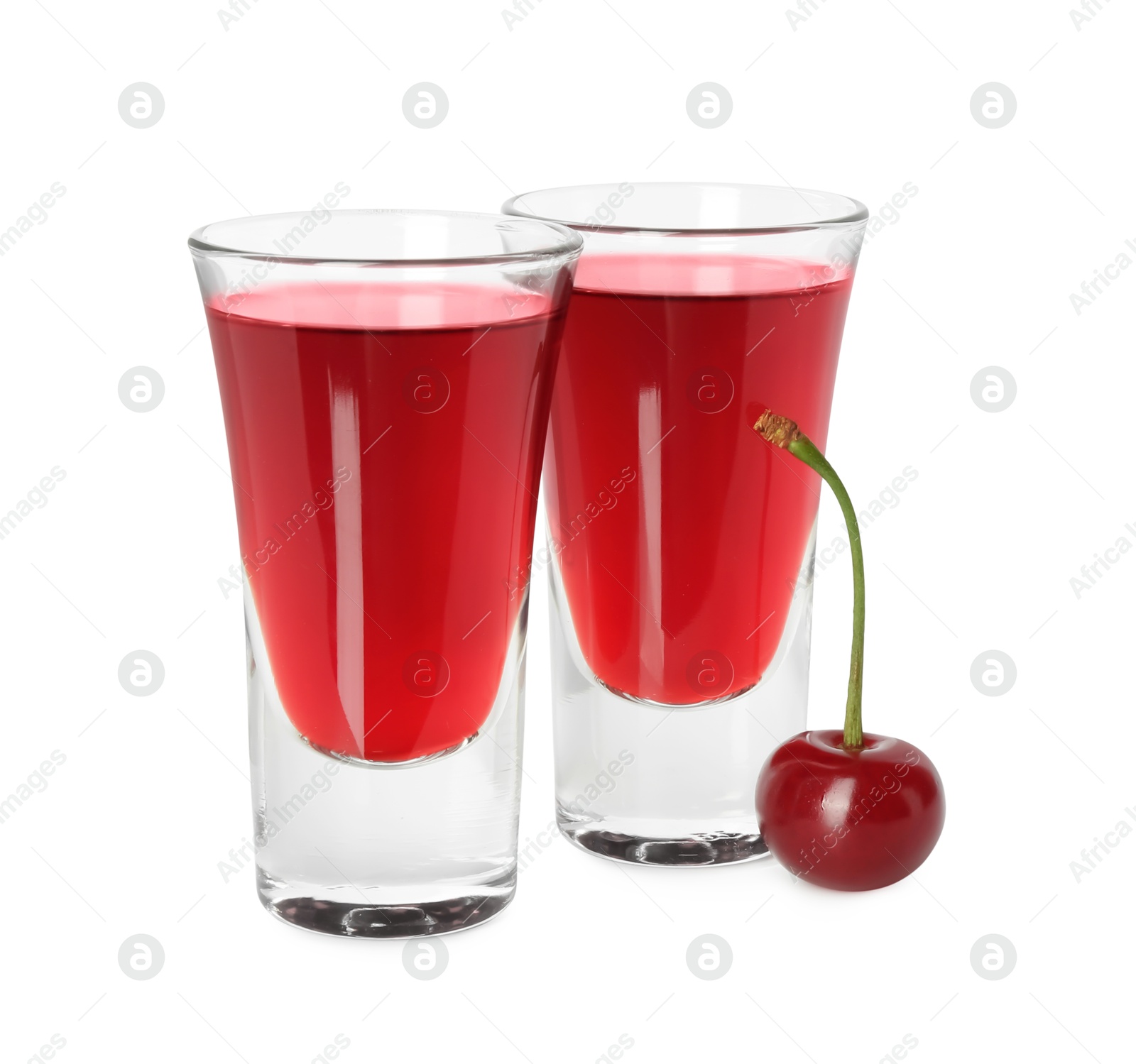 Photo of Shot glasses of delicious cherry liqueur and juicy berry isolated on white