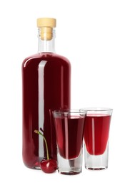 Photo of Bottle and shot glasses of delicious cherry liqueur isolated on white