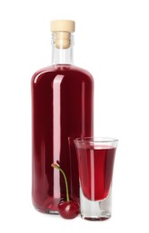 Bottle and shot glass of delicious cherry liqueur isolated on white