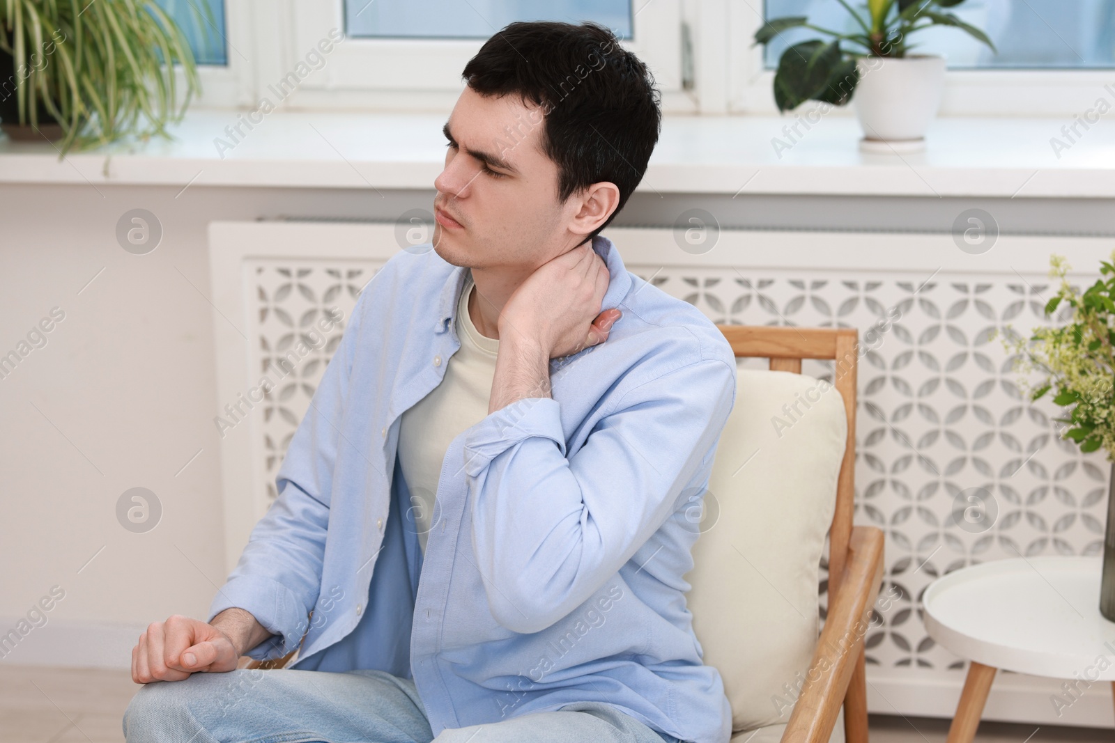 Photo of Man suffering from pain in his neck indoors