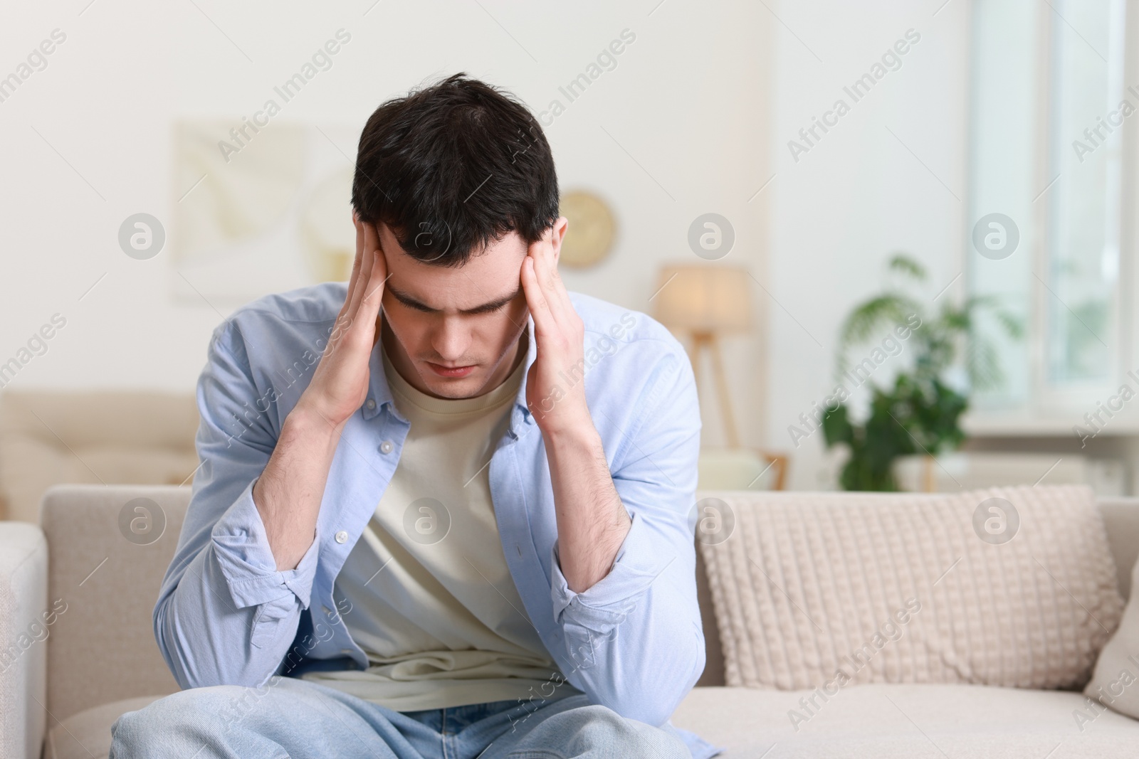 Photo of Man suffering from headache on sofa at home