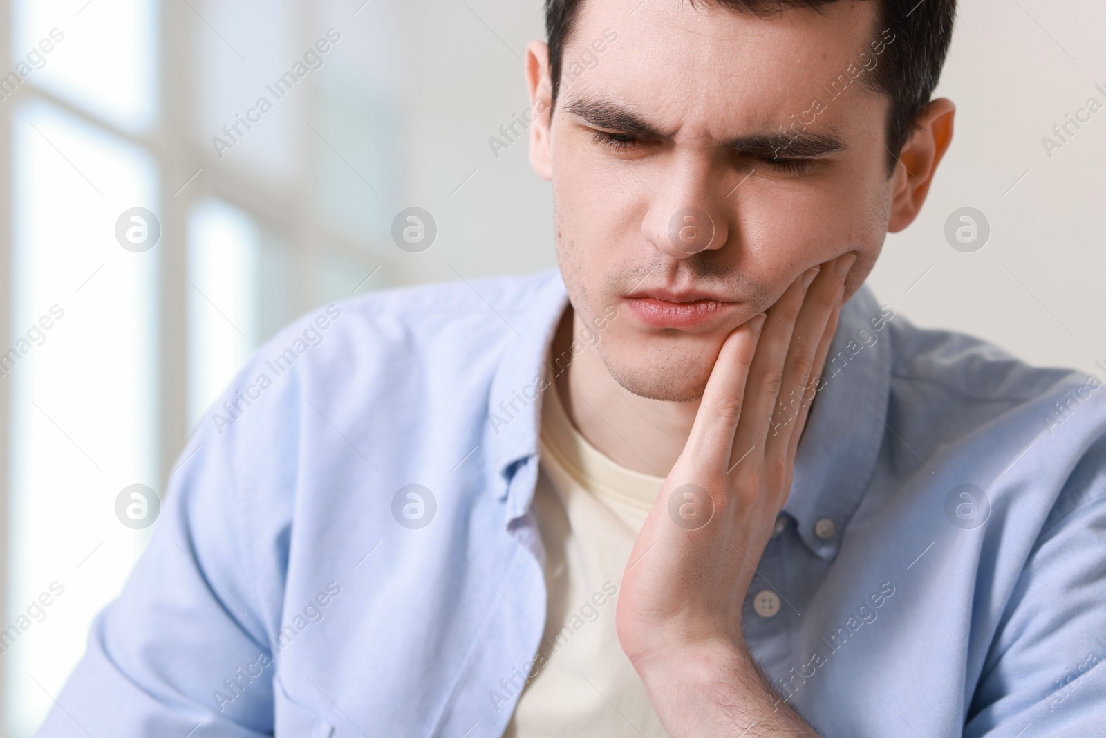 Photo of Sad man suffering from toothache at home