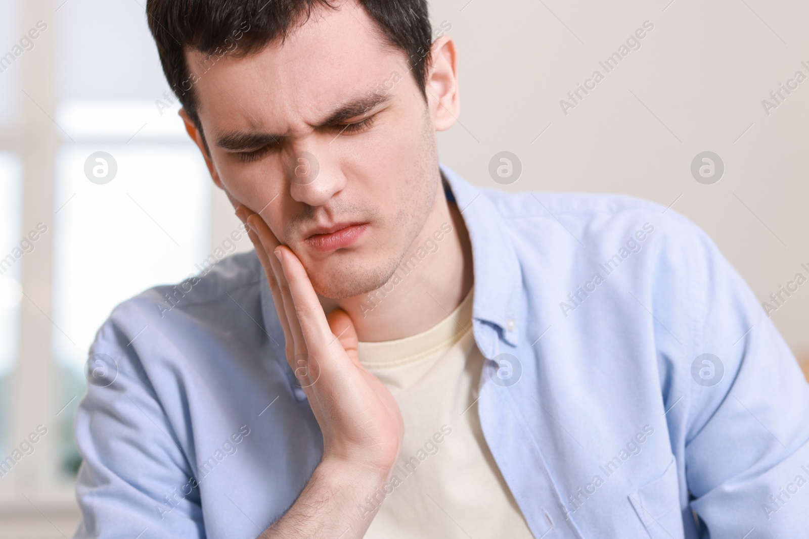 Photo of Sad man suffering from toothache at home