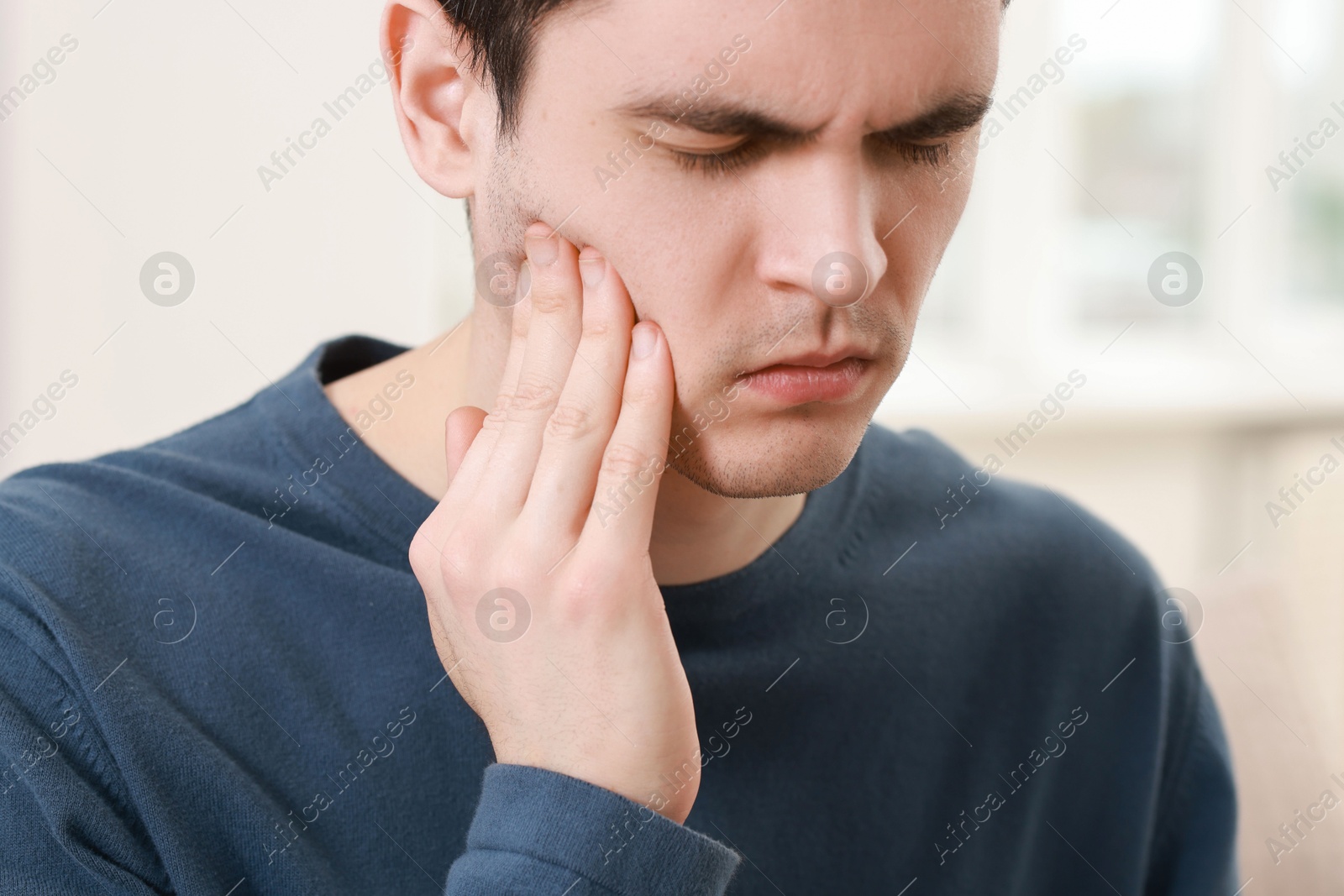 Photo of Sad man suffering from toothache at home