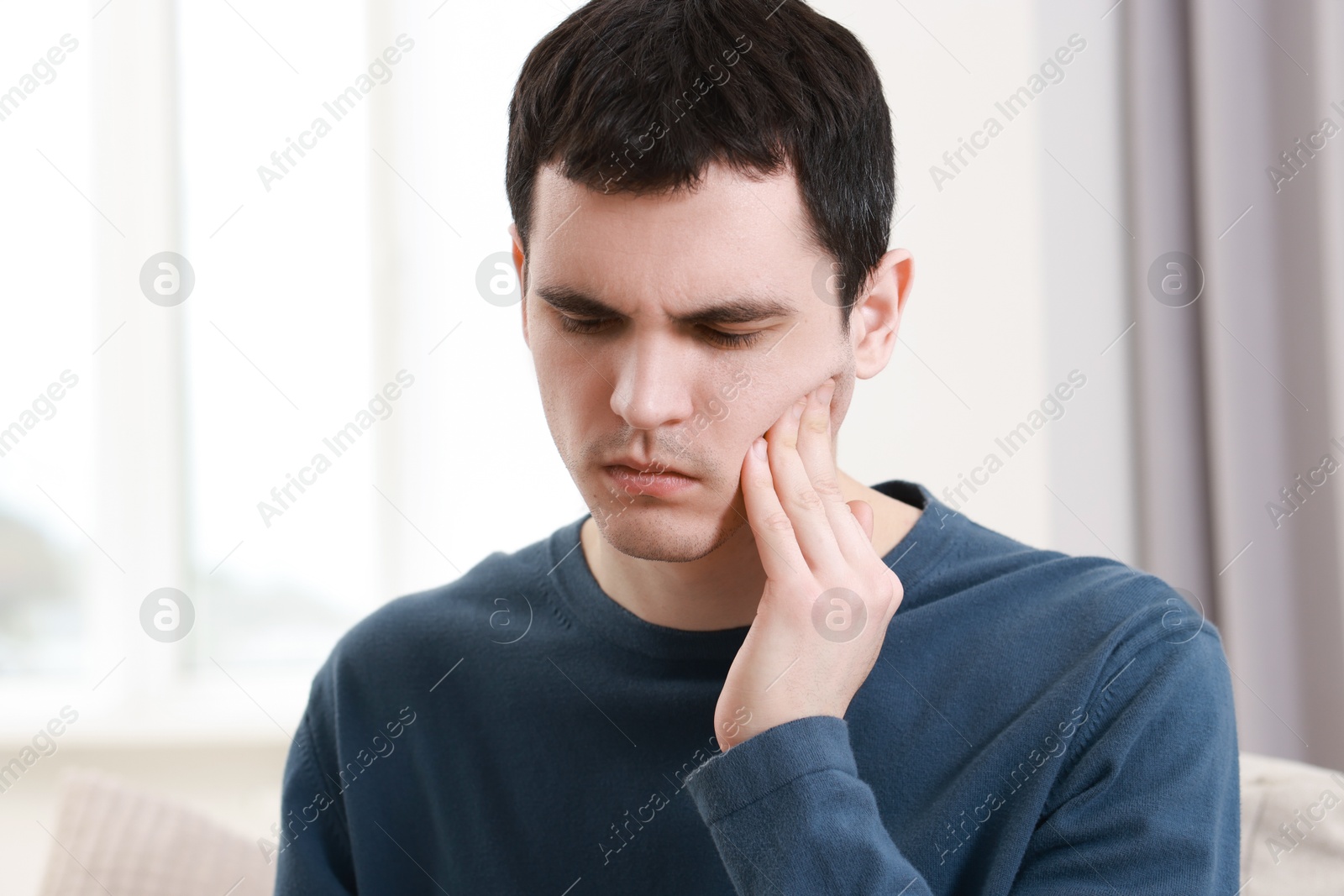 Photo of Sad man suffering from toothache at home