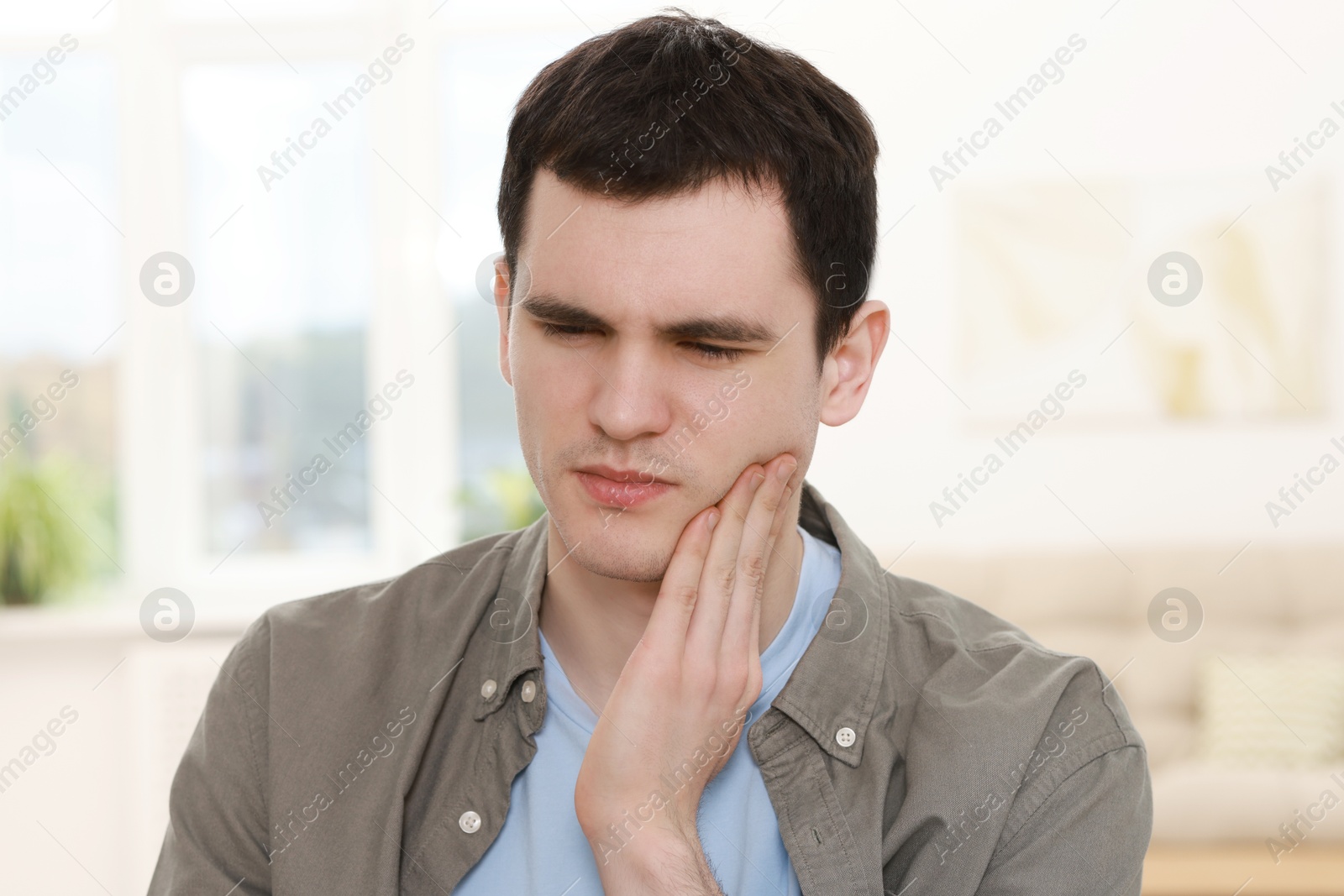 Photo of Sad man suffering from toothache at home