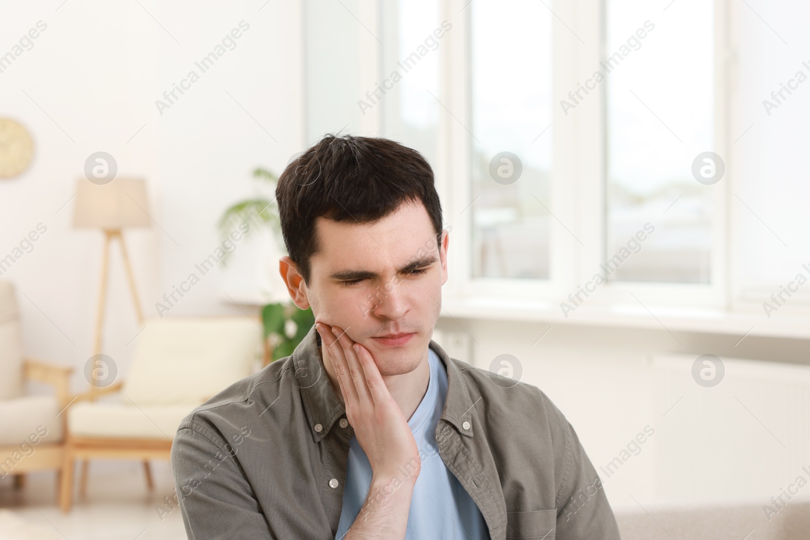 Photo of Sad man suffering from toothache at home