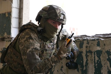 Military mission. Soldier in uniform with radio transmitter inside abandoned building
