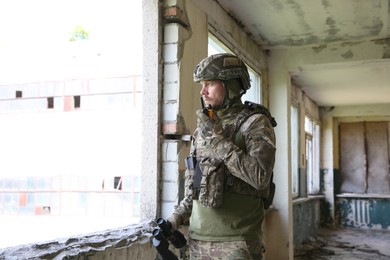 Photo of Military mission. Soldier in uniform with radio transmitter inside abandoned building