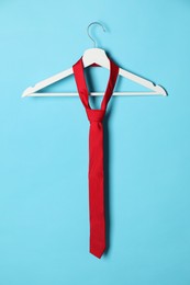 Hanger with red tie on light blue background