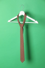 Hanger with brown striped tie on green background
